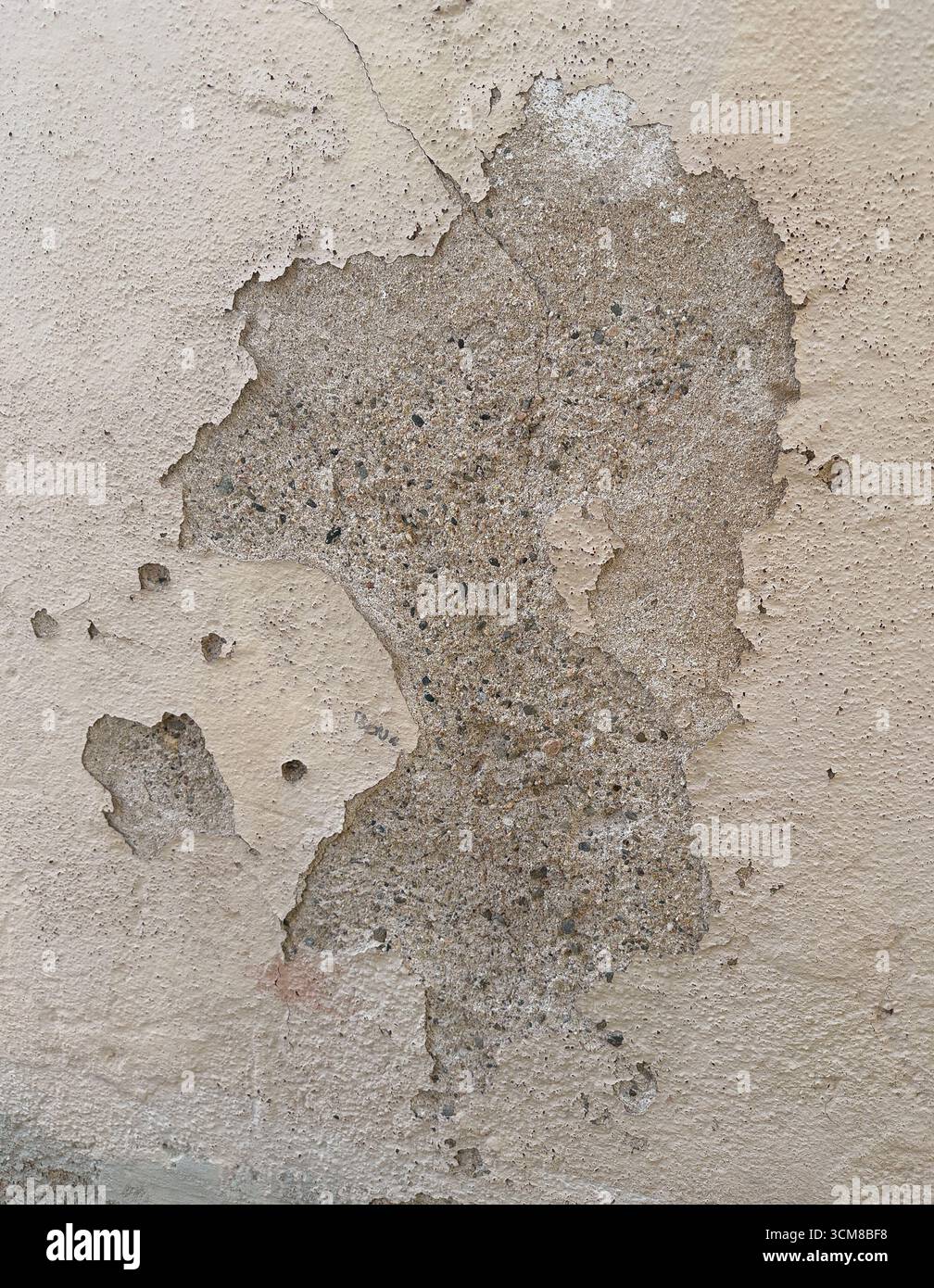 Nahaufnahme einer sich verschlechternden Putzwand mit Rissen, abblätternden Schichten und freiliegenden Ziegeln Stockfoto