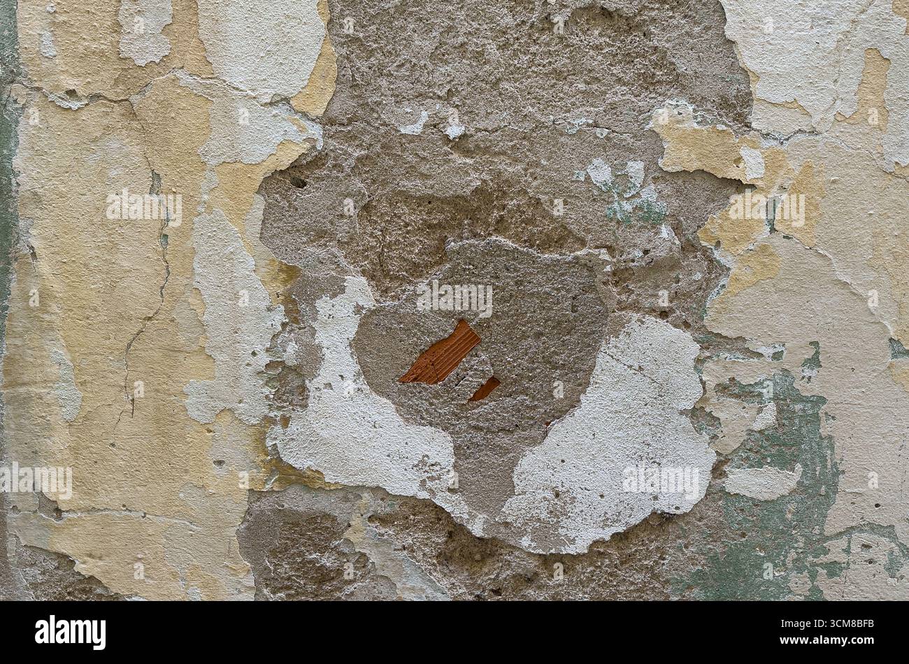Nahaufnahme einer sich verschlechternden Putzwand mit Rissen, abblätternden Schichten und freiliegenden Ziegeln Stockfoto