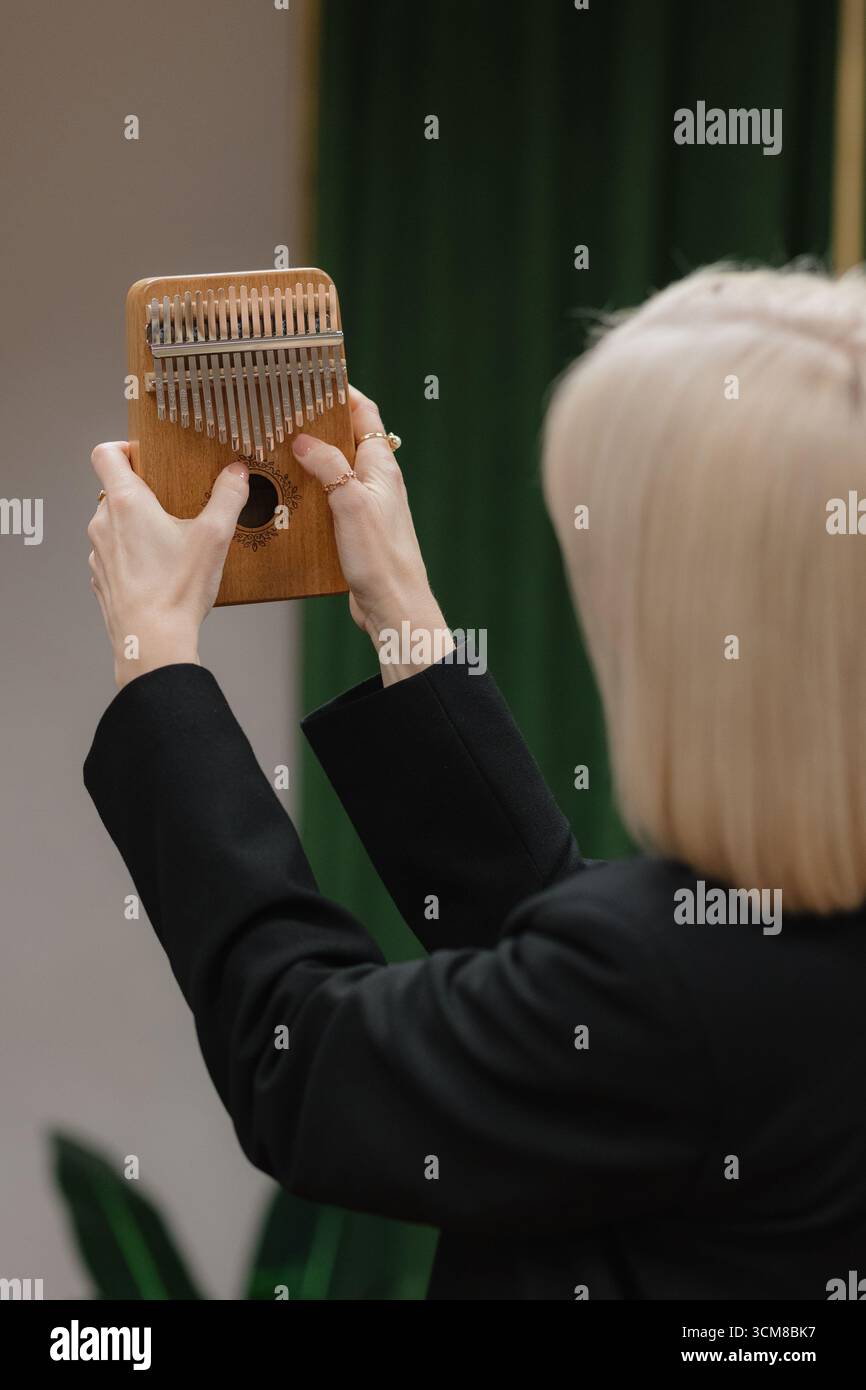 Die Frau hält anmutig einen Kalimba, zupft seine Metallzinken und kreiert beruhigende Melodien, die die Luft mit Ruhe erfüllen. Stockfoto