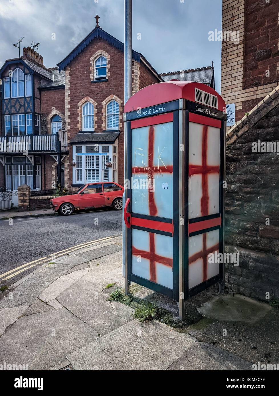 Paignton, Großbritannien. September 2025. Traditionelle rote Telefonbox mit Fenstern, die mit Graffiti der rot-weißen Flagge von St. George, der Nationalflagge Englands, bedeckt sind. Autor: Thomas Faull/Alamy Live News Stockfoto