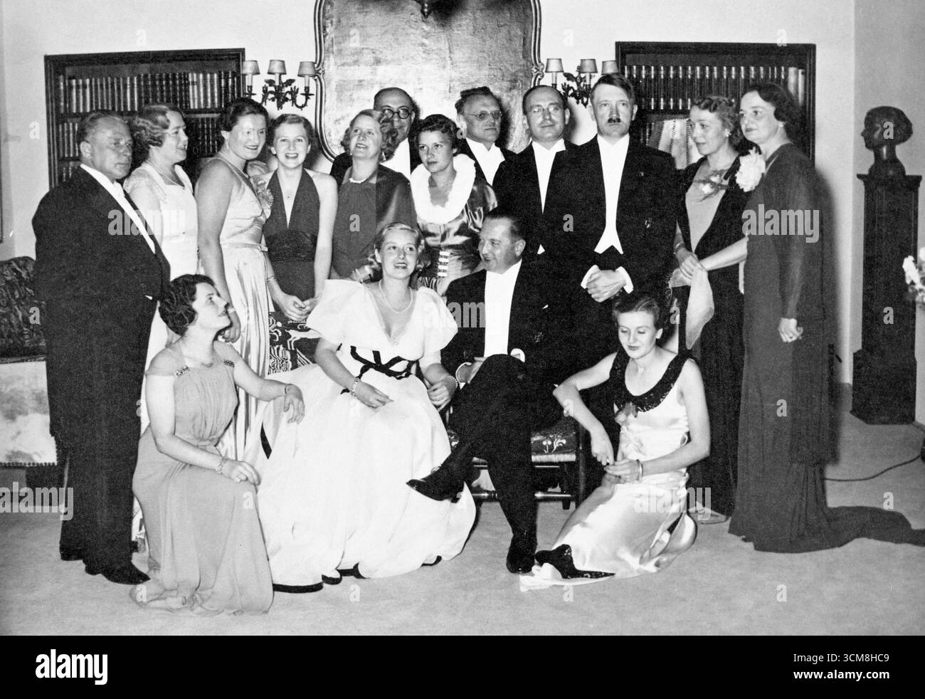 Adolf Hitler bei der Hochzeit von Marion Schönemann, einer Freundin von Eva Braun, in München. Gretl Braun ist auch zu Füßen Hitlers zu sehen Stockfoto