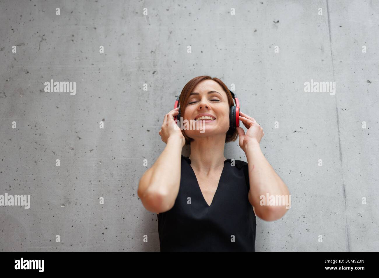 Ein Porträt einer jungen Geschäftsfrau, die Musik hört. Stockfoto