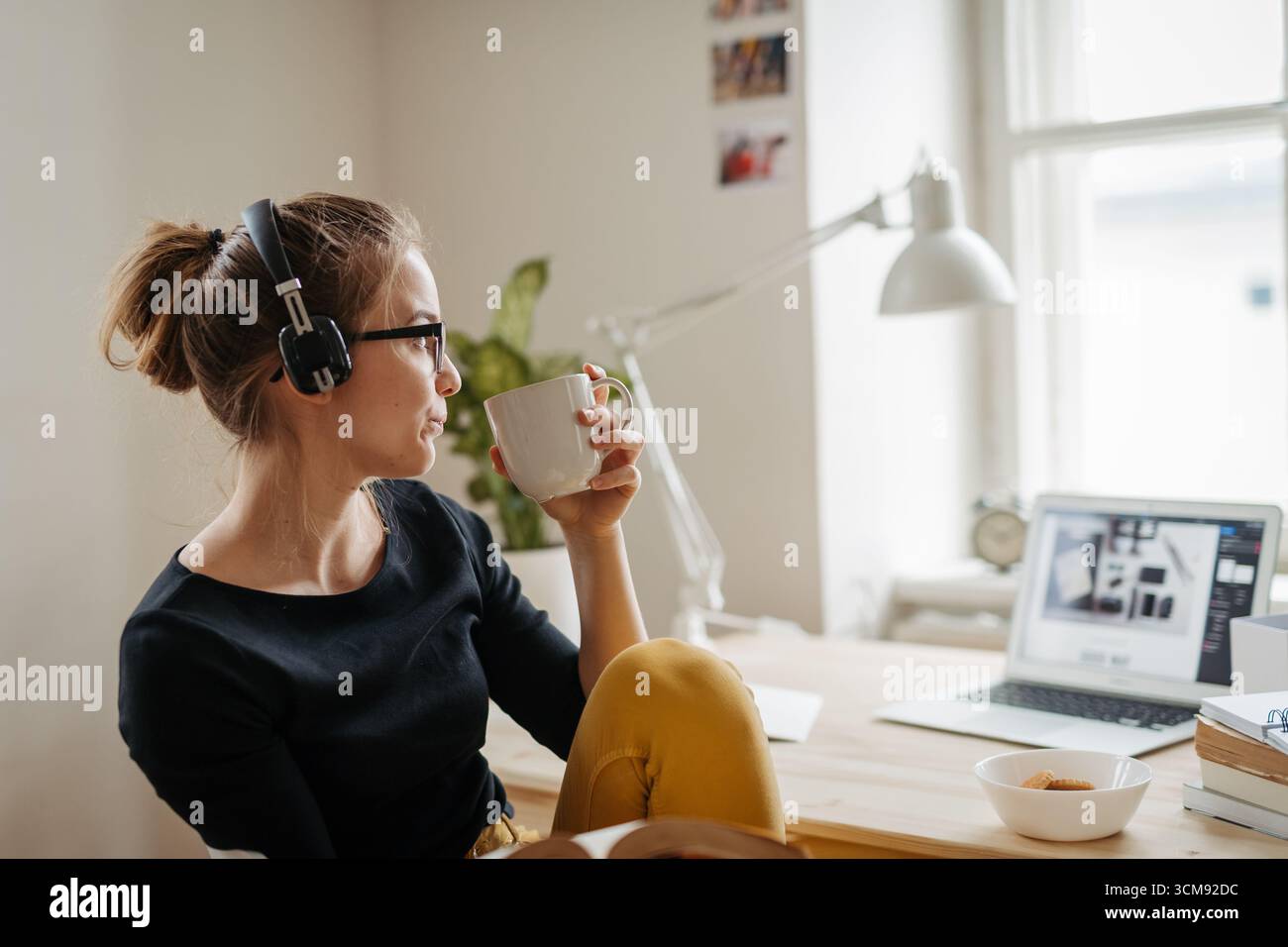 Studentin, die während des Studiums Pause macht, Musik hört und Kaffee trinkt. Stockfoto