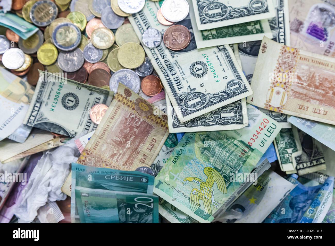 Geld aus verschiedenen Ländern der Welt ist in einem Stapel von Münzen und Banknoten verstreut. Amerikanische Dollar, rumänischer lei, serbische Dinar, Euro und HR Stockfoto