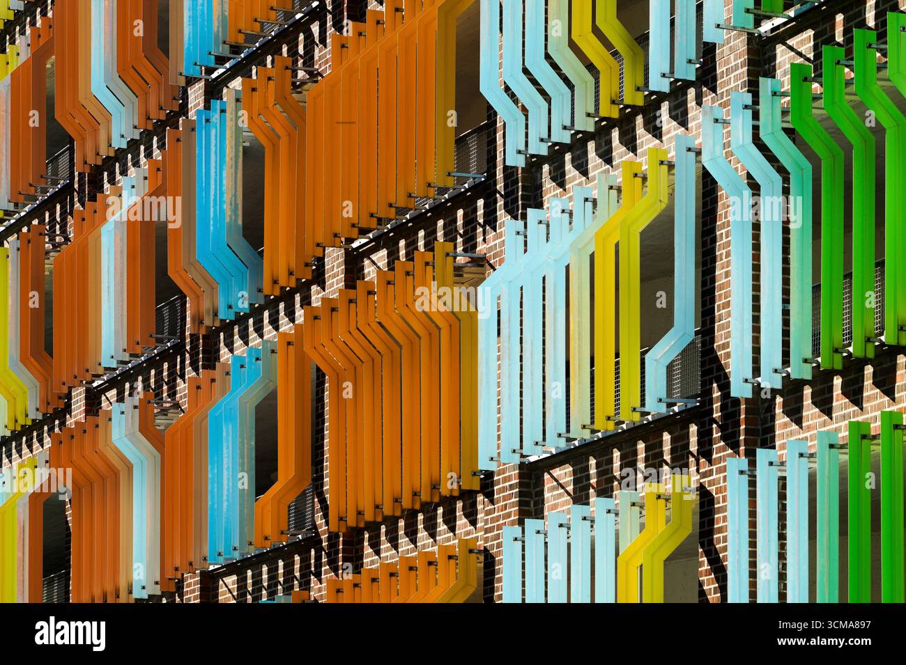 Bunte Schichten: Architektonische Rhythmen das Petri P-Hus in Malmö präsentiert ein lebendiges Spiel von Geometrie und Farbe und zeigt eine Fassade voller rhythmischer Muster. Diese architektonische Leinwand kombiniert Orange, Blau, Grün und Gelb und hebt sich so deutlich von der städtischen Landschaft ab. Jede Schicht mit ihren scharfen Winkeln und kontrastfarbenen Farben verleiht dem Gebäude eine dynamische visuelle Wirkung und verwandelt das Gebäude in ein großangelegtes Kunstwerk der Stadt. Stockfoto