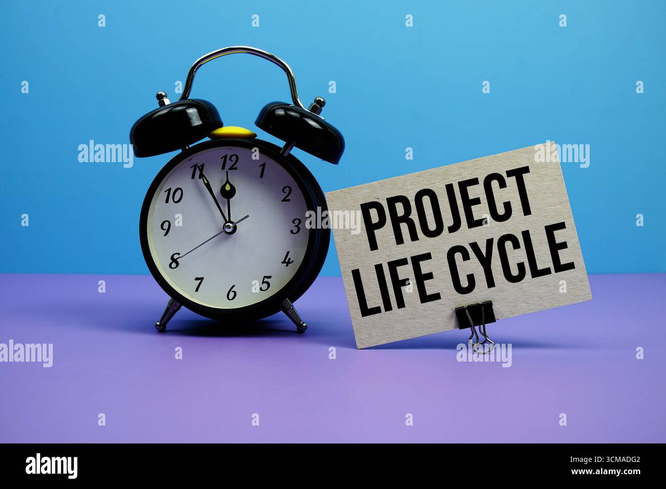 Text des Projektlebenszyklus mit Wecker auf blauem und violettem Hintergrund Stockfoto