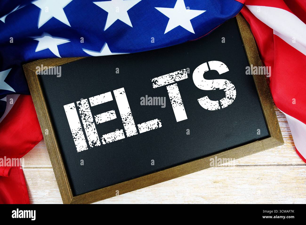 Amerikanische Flagge mit Tafel „IELTS“ auf hölzernem Hintergrund Stockfoto