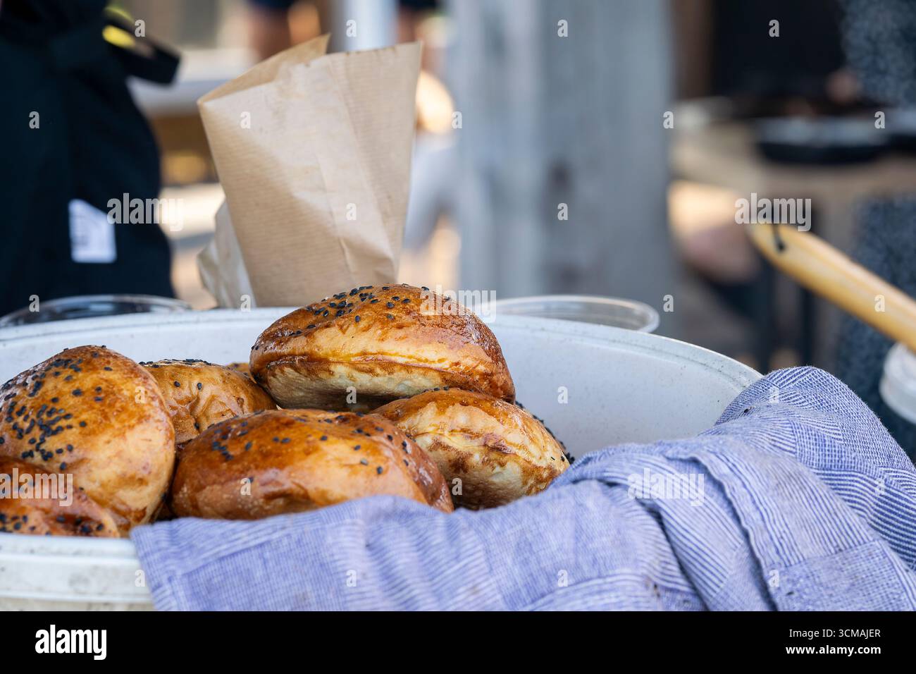 Hamburger Brötchen mit schwarzen Sesamsamen. Runde Sandwichbrötchen mit schwarzem Sesam. Hausgemachtes Brötchen für Burger in Schüssel. Stockfoto
