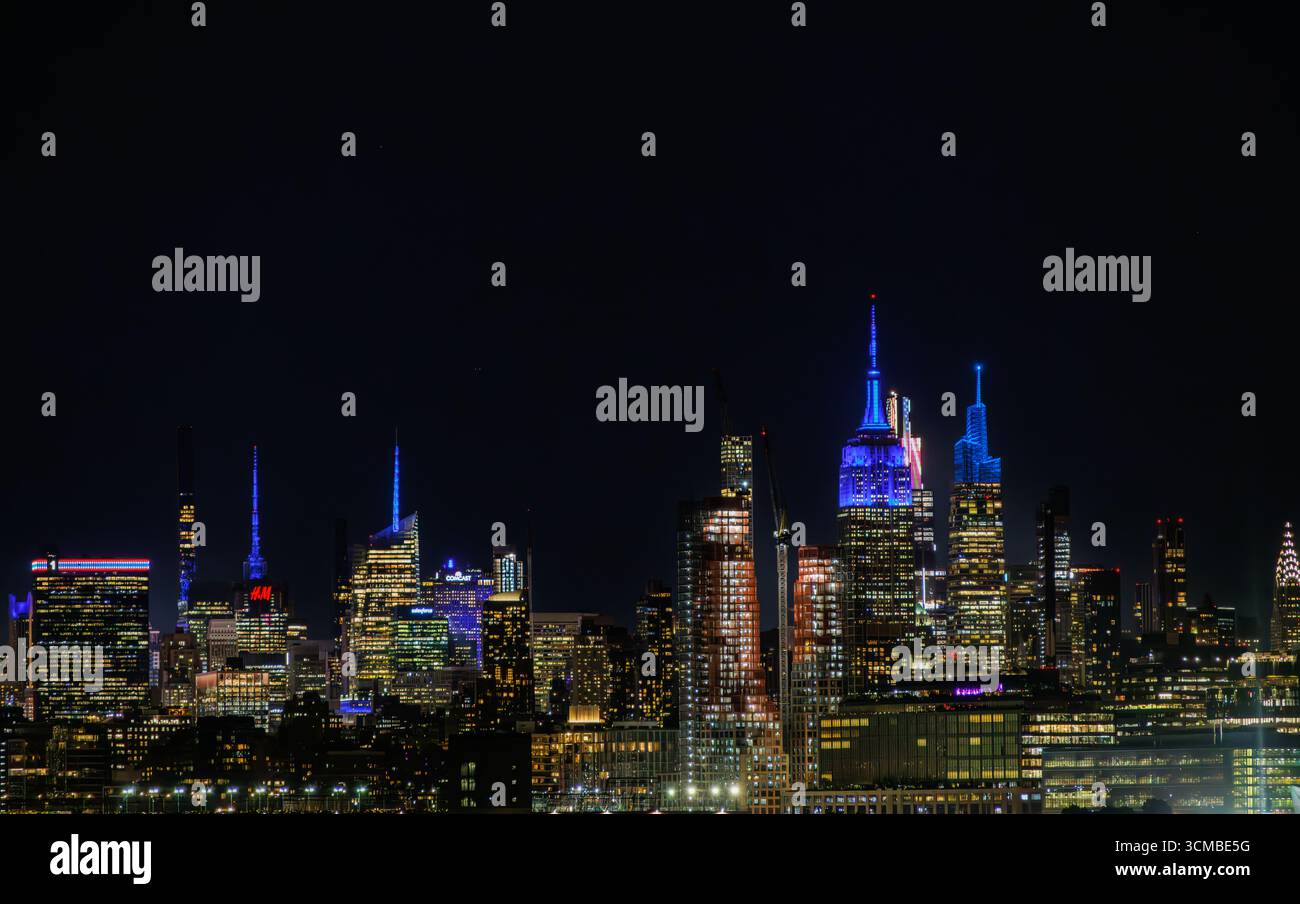 Lebhafter Nachtanblick auf die Skyline von New York City mit beleuchteten Wolkenkratzern mit bunten Lichtern, einschließlich des Empire State Building. Stockfoto