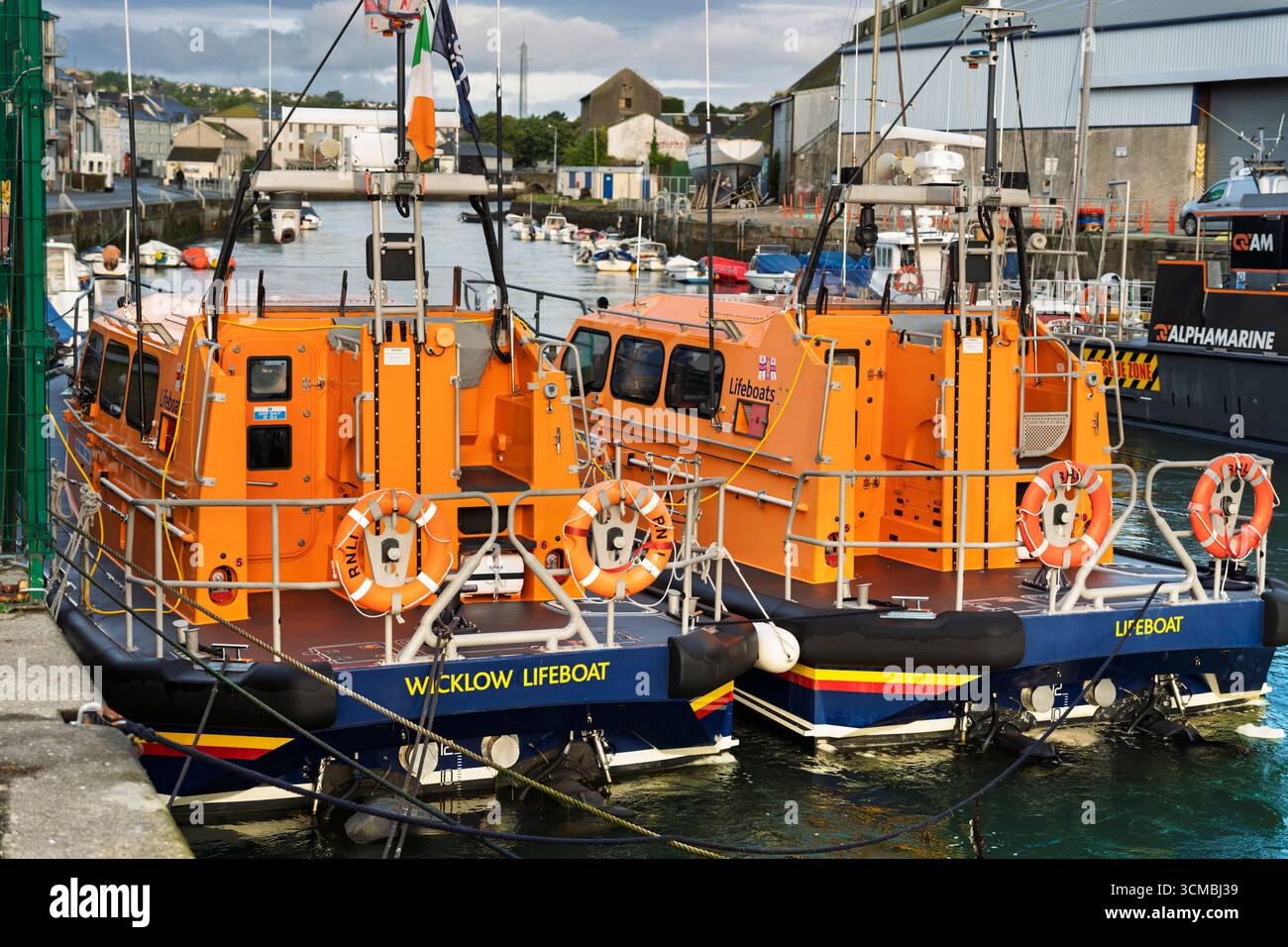 Zwei RNLI Rettungsboote, die im Hafen von Wicklow, Irland, mit irischer Flagge, Rettungsausrüstung und Hafenhintergrund vor Anker liegen. Stockfoto