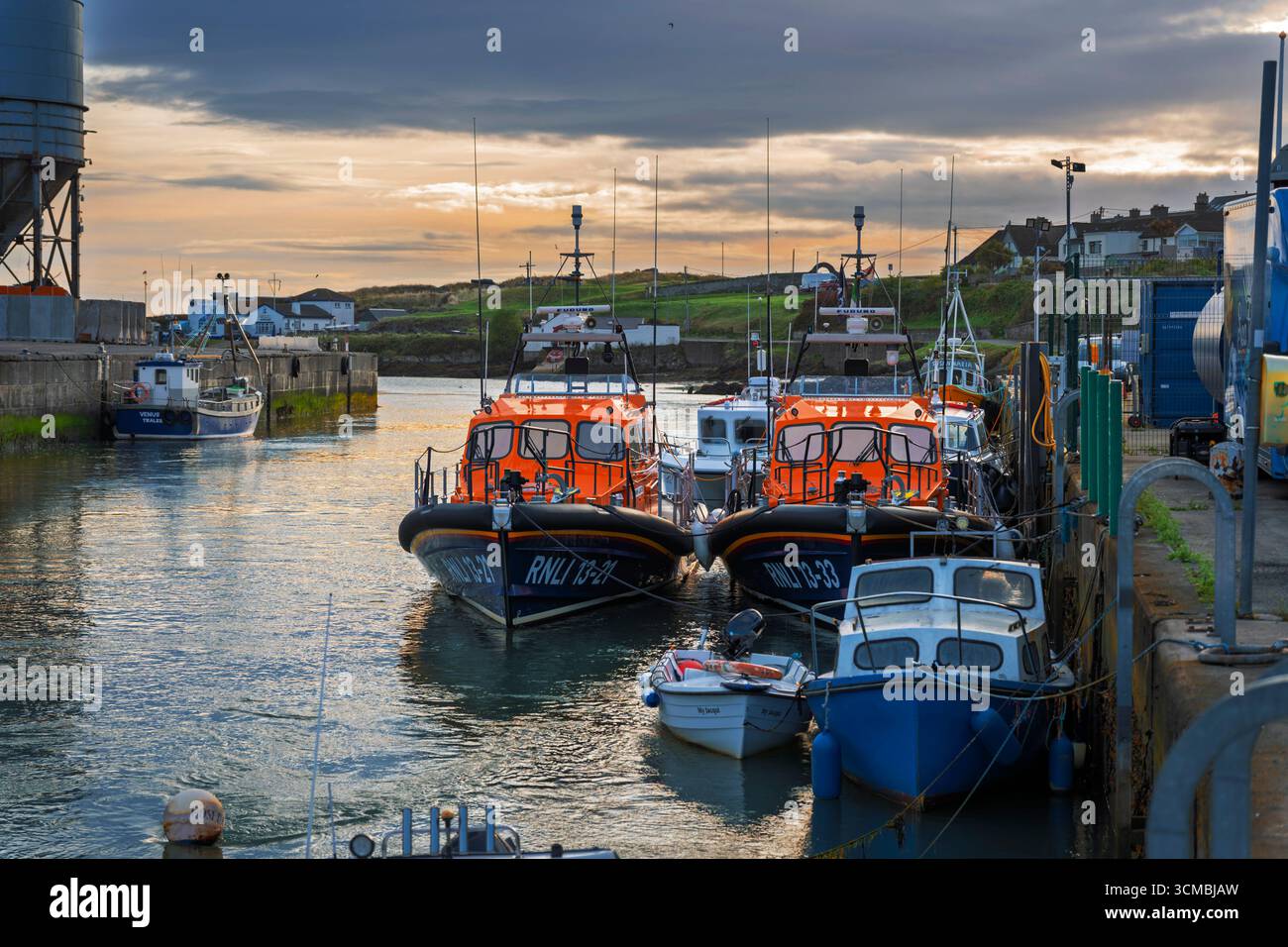 Zwei RNLI Rettungsboote, die im Hafen von Wicklow, Irland, mit irischer Flagge, Rettungsausrüstung und Hafenhintergrund vor Anker liegen. Stockfoto