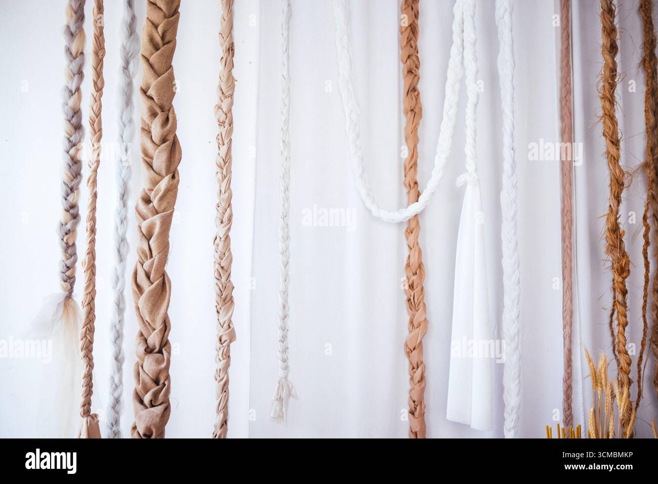 Die Wand ist mit geflochtenen Materialien in sanften Farbtönen verziert, die Handwerkskunst und Design hervorheben, perfekt für Wohnkultur-Ideen und künstlerische Inspirationen in Inte Stockfoto
