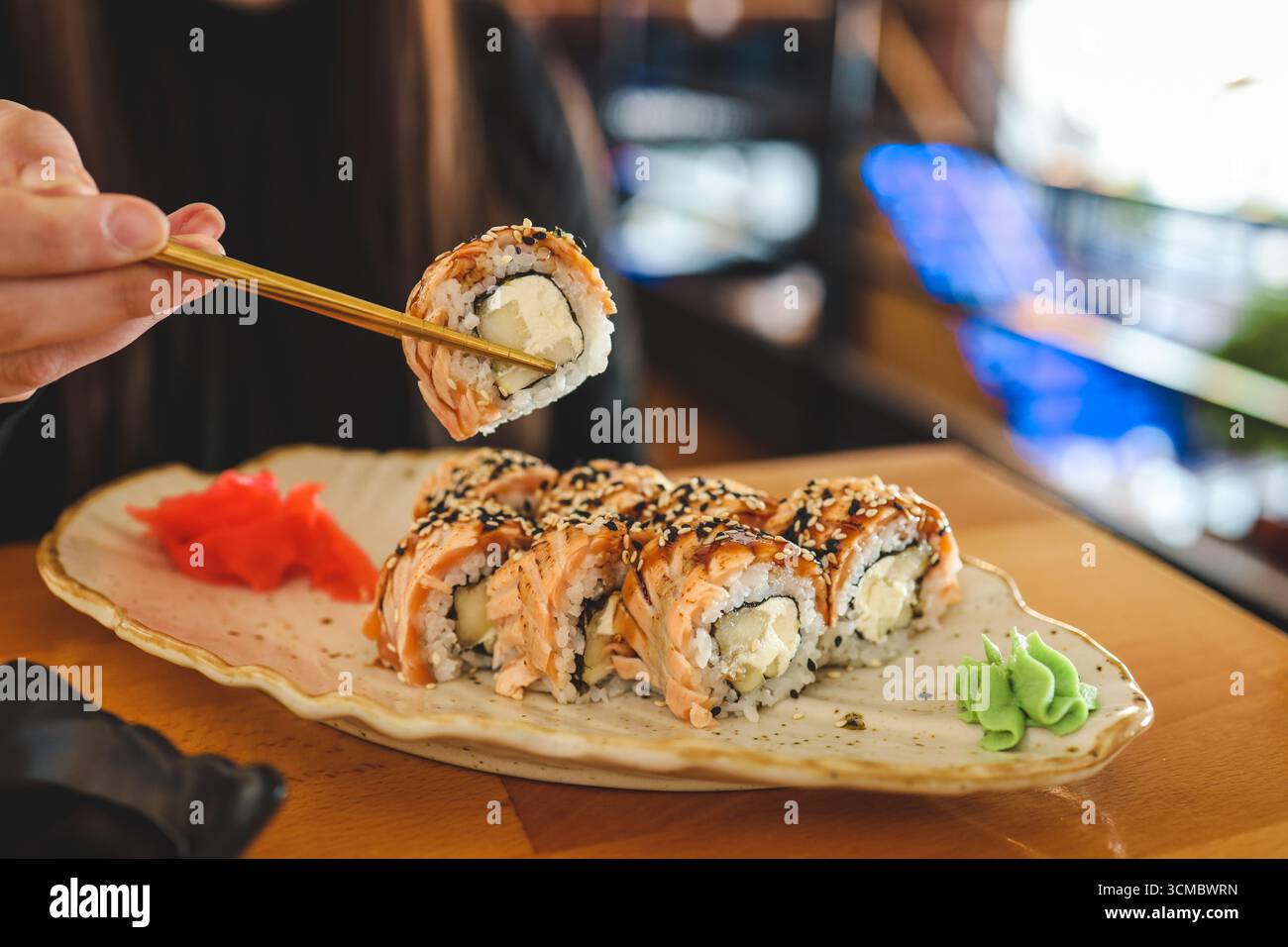 Schöne junge Frau, die Sushi-Rolle im Café isst. Frau, die Sushi mit Essstäbchen im Restaurant isst. Stockfoto