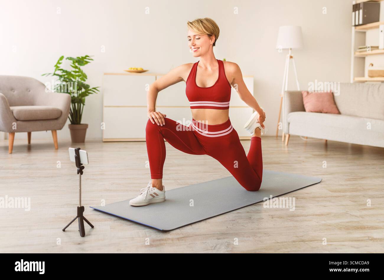 Fröhliche Frau, die das Bein vor dem Smartphone streckt Stockfoto