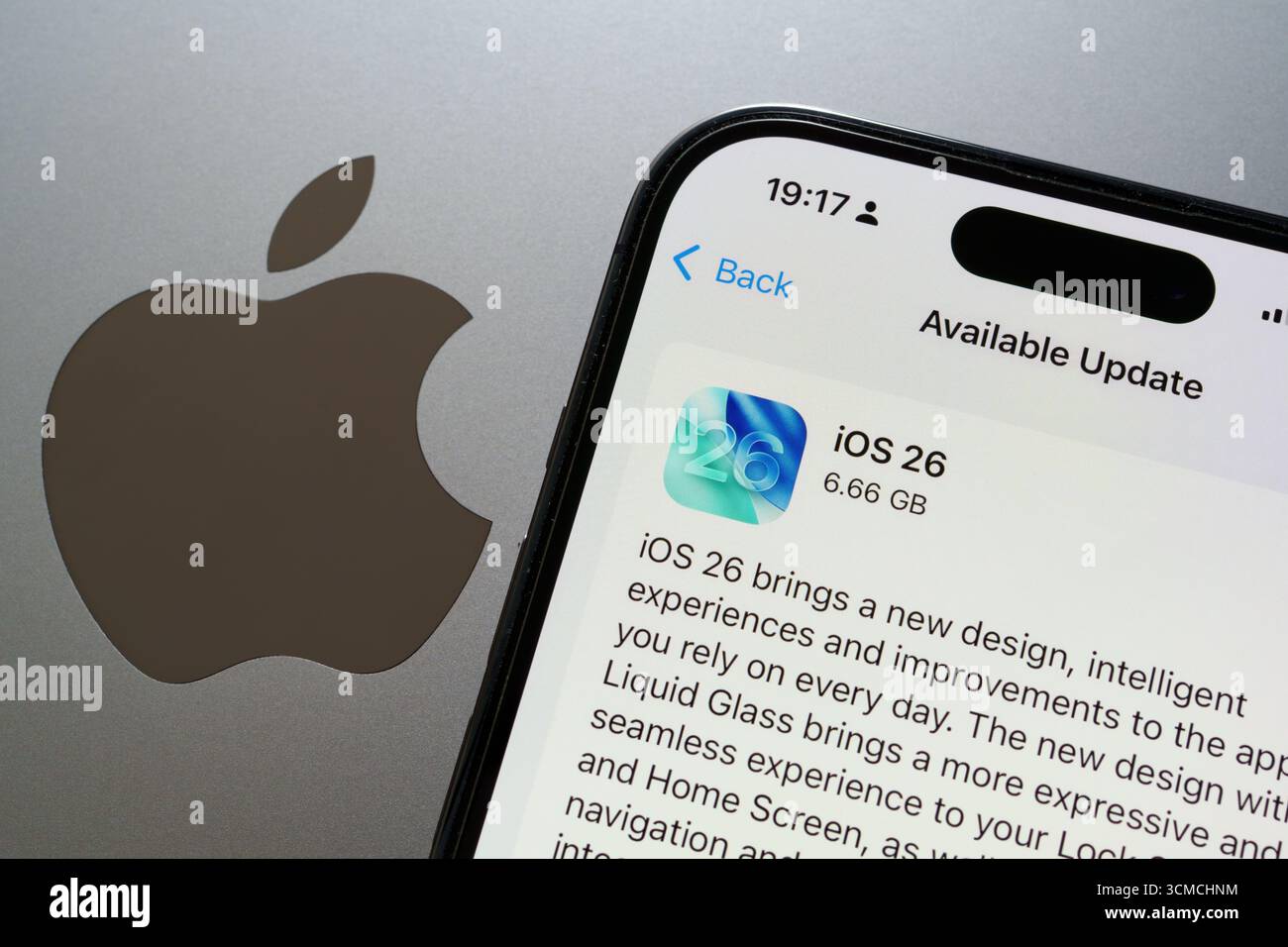 Nahaufnahme iOS 26-Update auf dem iPhone mit Apple-Logo auf dem MacBook, Lichtmodus-Schnittstelle. Stafford, Vereinigtes Königreich, 15. September 2025 Stockfoto