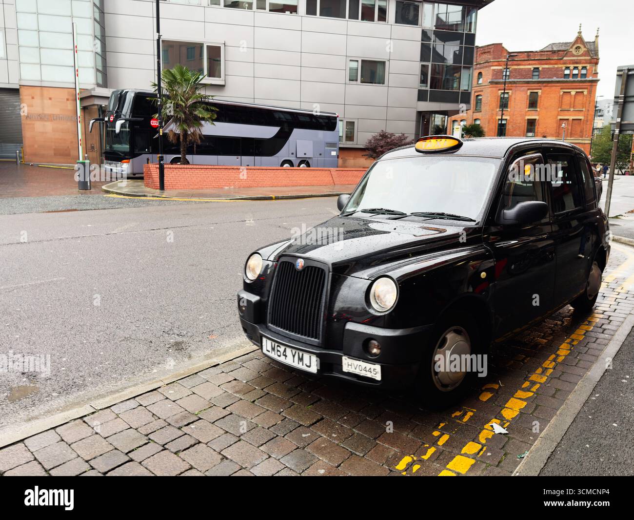 Manchester, Großbritannien - 14. September 2025: Ikonisches schwarzes Taxi parkt auf der regnerischen Straße im Stadtzentrum von Manchester, Großbritannien. Stockfoto
