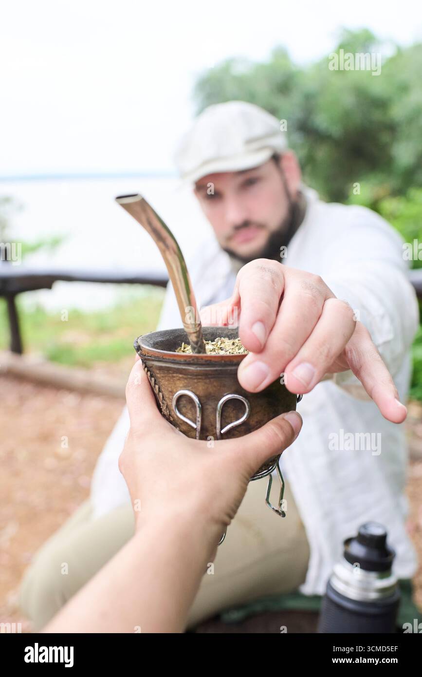 Mann teilt sich mit jemandem einen Partner. Dieser argentinische Aufguss ist ein Symbol für das Teilen und Zusammensein. Komposition mit selektivem Fokus auf die Hände. Stockfoto