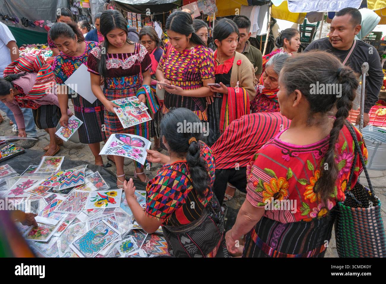 Chichicastenango, Guatemala - 3. Juli 2025: Frauen kaufen Stickmuster auf dem Santo Tomas Markt in Chichicastenango, Guatemala. Stockfoto