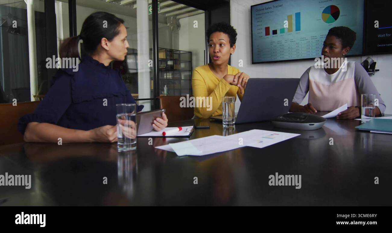 Drei Geschäftsfrauen untersuchen Karten und Daten im Konferenzraum mit Laptop-Tablet-Freisprecheinrichtung Stockfoto