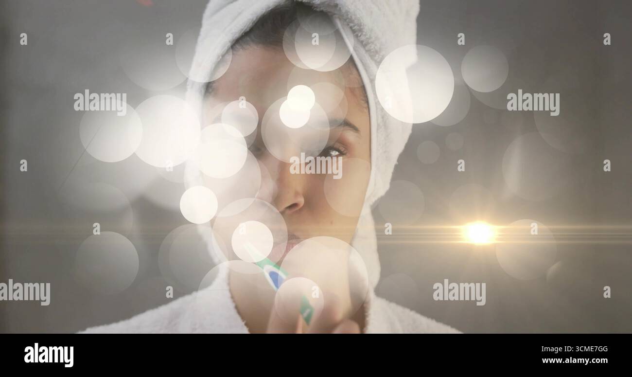 Frau, die im Badezimmer Handtuch und Bademantel trägt, mit Zahnbürste Bokeh und Linsenflecken Stockfoto