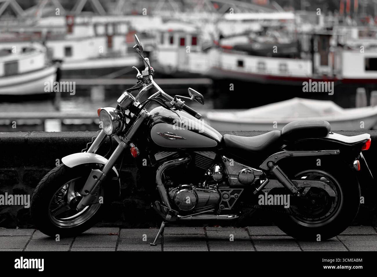 Hyosung Aquila GV650 Cruiser Motorrad in selektiver Farbbehandlung, Seitenprofil mit Chrom-Motorteilen, geparkt von Booten an einem Jachthafen nach Regen. Stockfoto