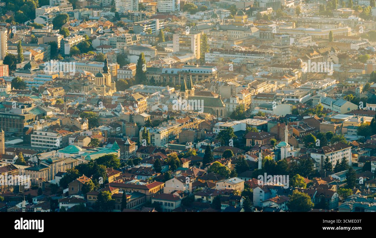 Blick auf die Altstadt von Sarajevo mit der Kathedrale des Heiligen Herzens, Moscheen und traditionellen Dächern im goldenen Abendlicht Stockfoto