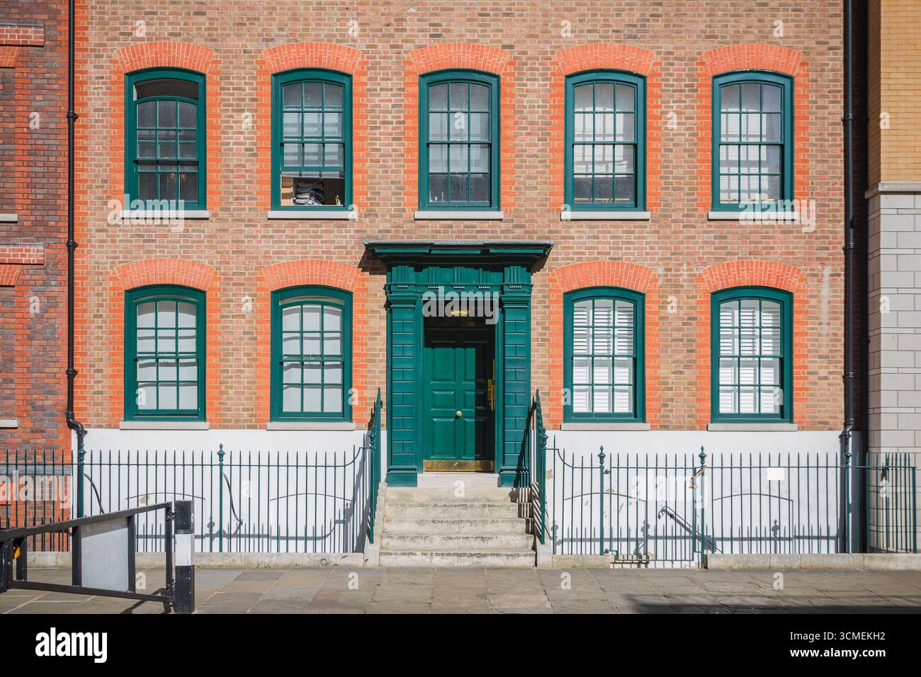 Die vordere Anhöhe eines Reihenhauses im georgianischen Stil in London ist mit grünen Türen und Fensterrahmen dekoriert Stockfoto