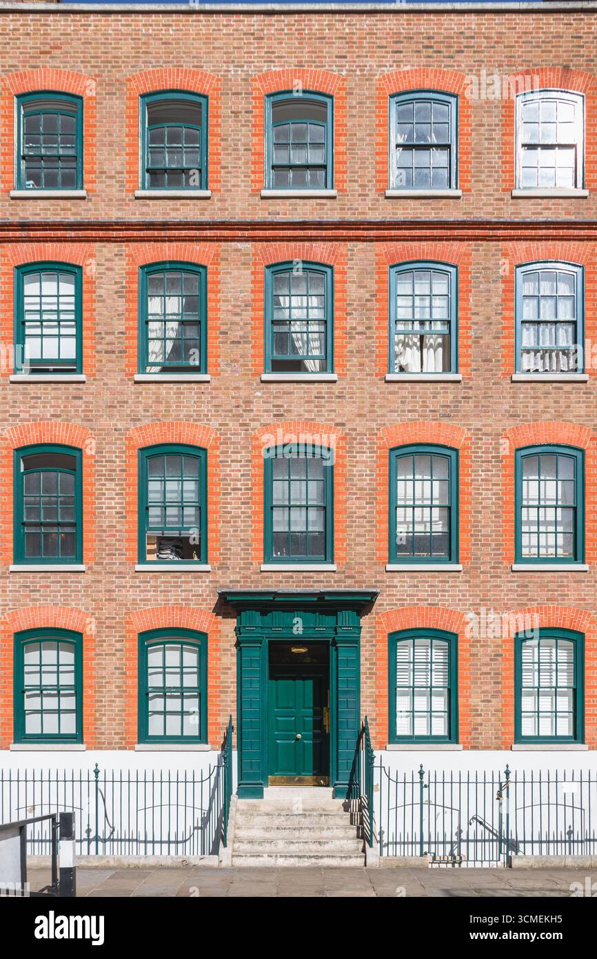 Die vordere Anhöhe eines Reihenhauses im georgianischen Stil in London ist mit grünen Türen und Fensterrahmen dekoriert Stockfoto