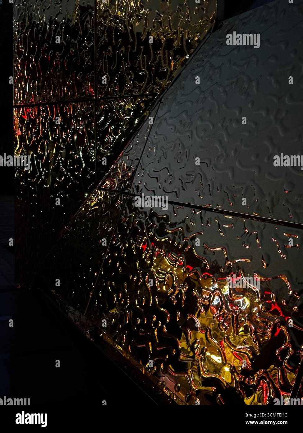 Nahaufnahme abstrakter goldener Oberfläche mit geprägten Mustern und reflektierenden Lichtern. Stockfoto