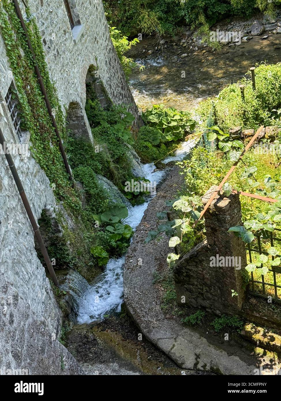 Wasser strömt aus den drei Tunneln einer alten, nicht funktionierenden Wassermühle in den Fiume Rosaro (Fluss Rosaro) in der Provinz Massa-Carrara C a Mo Stockfoto