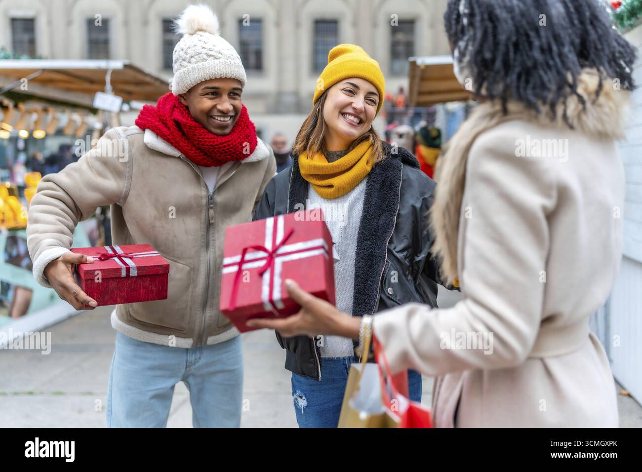 Glückliche Freunde tauschen weihnachtsgeschenke auf einem geschäftigen Markt aus, genießen die festliche Atmosphäre und feiern die Freude der Saison Stockfoto Glückliche Freunde tauschen weihnachtsgeschenke auf einem geschäftigen Markt aus, genießen die festliche Atmosphäre und feiern die Freude der Saison Stockfoto