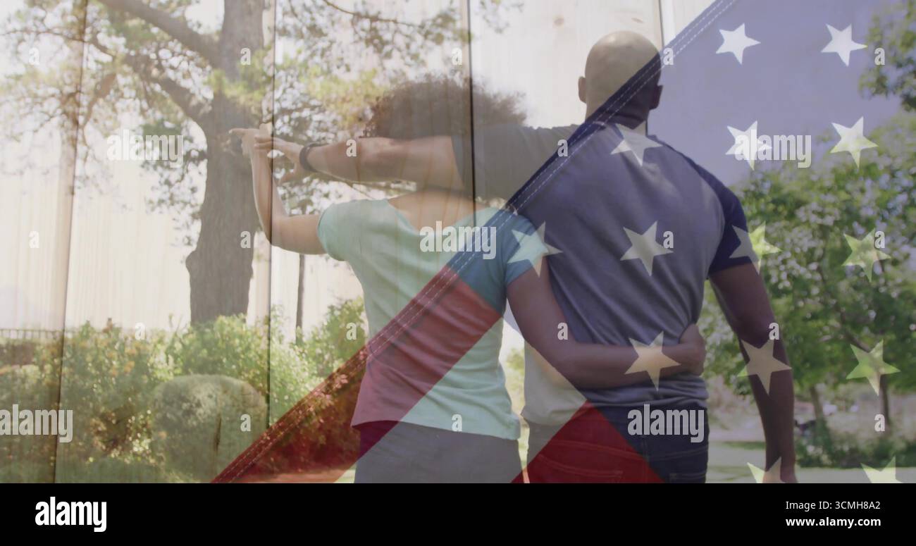 Spazieren Sie romantisches Paar, das Arme entlang des gepflasterten Gehweges im Vorortpark verbindet, mit amerikanischer Flagge Stockfoto