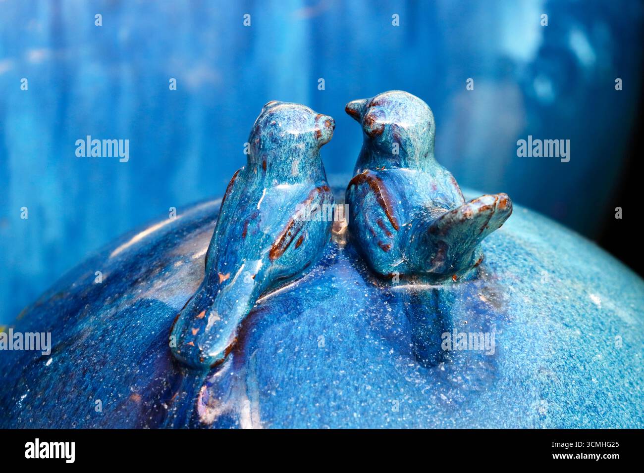 Zwei Keramikvögel auf einer blauen Dekorationskugel Stockfoto