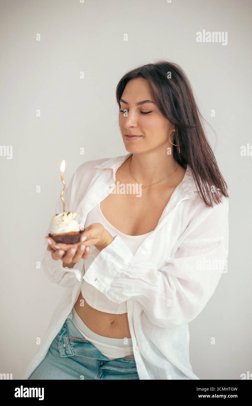 Eine junge Frau, die Kerze auf ihrem Geburtstagskuchen ausbläst. Geburtstagsfeier Stockfoto