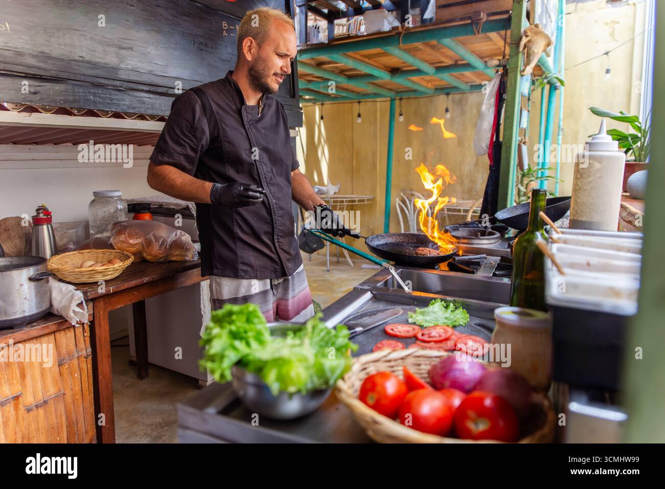 Koch grillt einen saftigen Burger über offener Flamme Stockfoto
