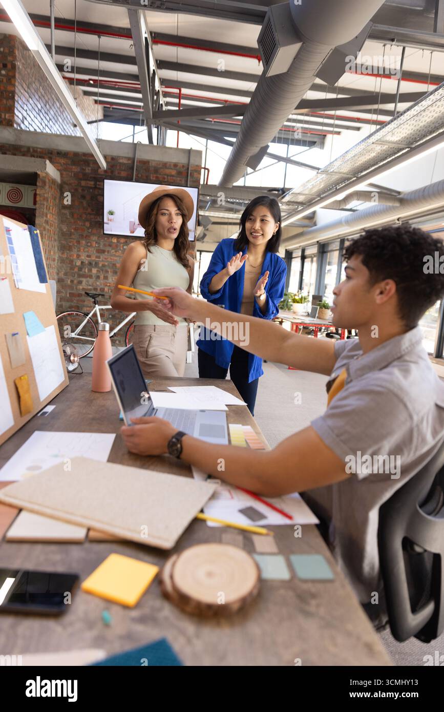 Verschiedene Kollegen arbeiten am Tisch im kreativen Büro mit Laptop, Bleistift und Farbmustern zusammen Stockfoto
