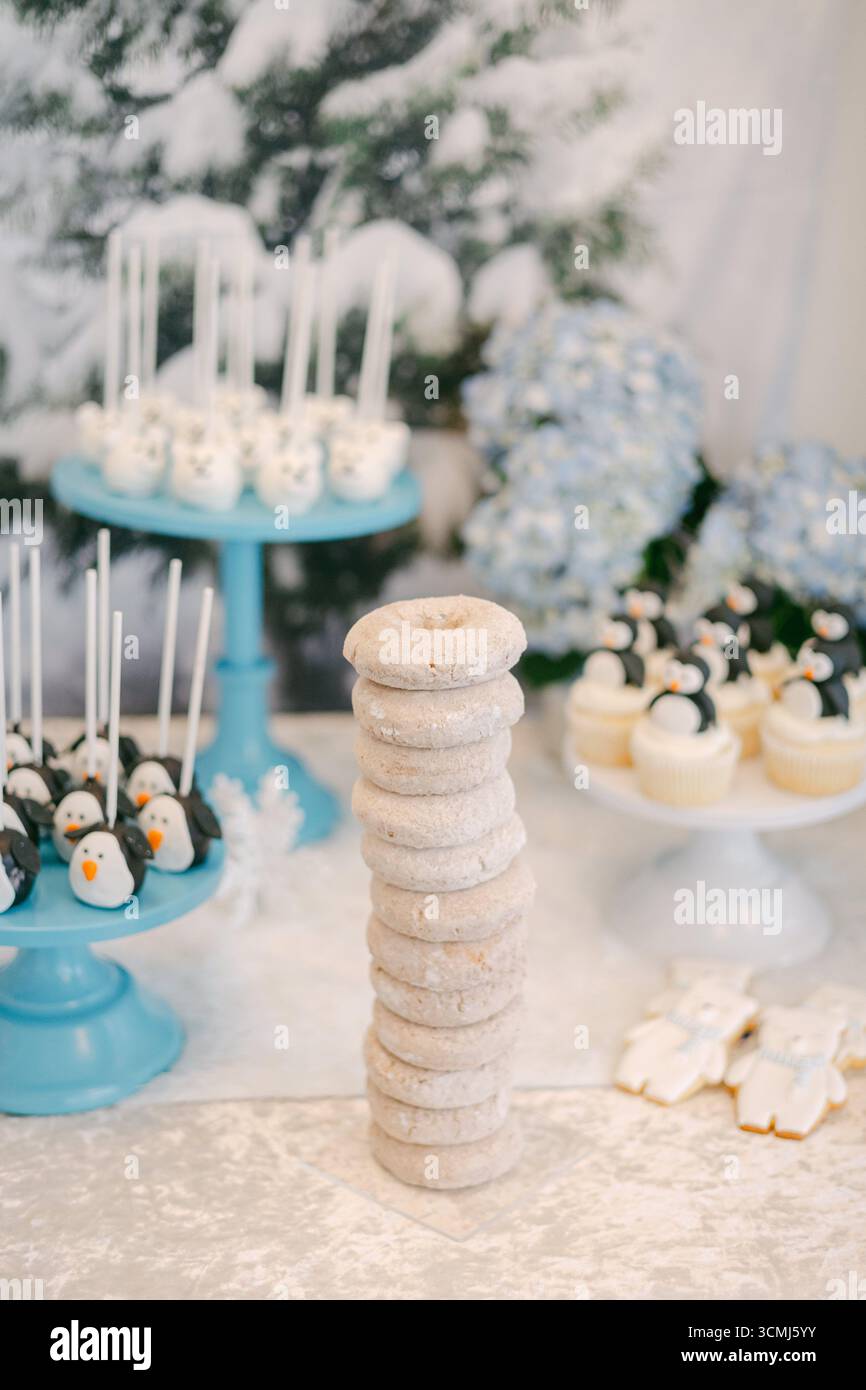 Ein Wintertisch mit einem hohen Stapel Donuts und schneeähnlichen Süßigkeiten sorgt für eine festliche Atmosphäre. Stockfoto