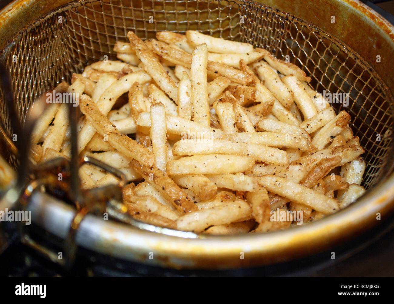 Knusprige goldene Pommes Frites in einem Fritteuse-Korb, bereit zum Verzehr Stockfoto
