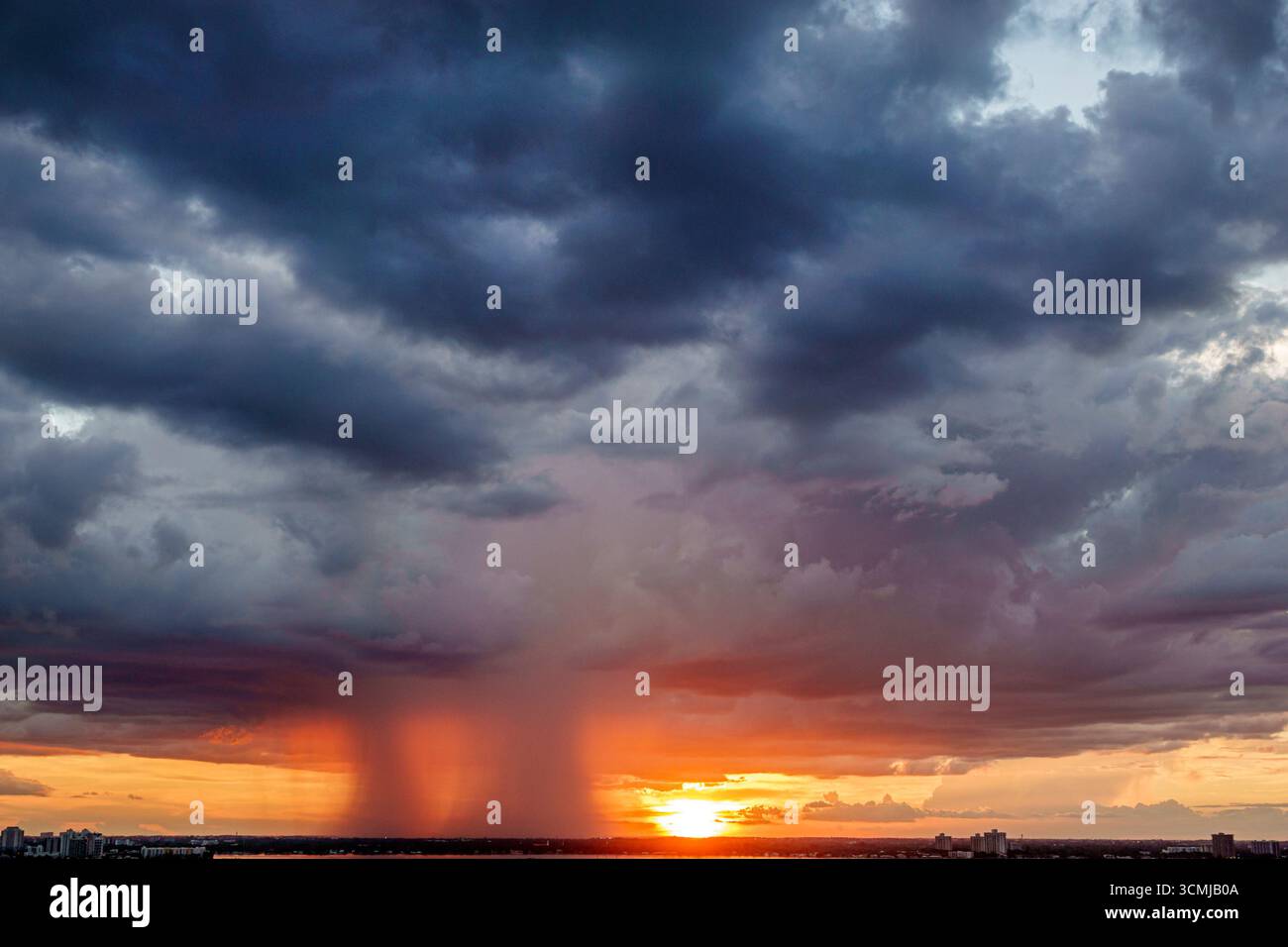 Miami Beach Florida, Wetter tropische Sturmwolken Niederschlag starker Regenguss, dramatische Himmel Sonnenuntergang Glow Lichtstrahlen, isolierte Regenschacht sichtbare Spalte, Regen Stockfoto