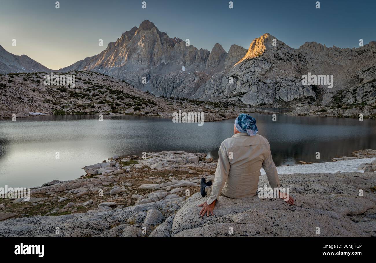 Rückansicht eines Wanderers, der auf einem Felsen am Grinnell Lake sitzt, mit Blick auf den Sierra National Forest, Sierra Nevada Mountains, Kalifornien, USA Stockfoto
