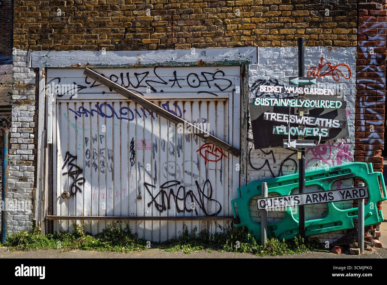 Graffiti-überdachte Garagentür mit festlicher Beschilderung in Urban Street Scene Stockfoto