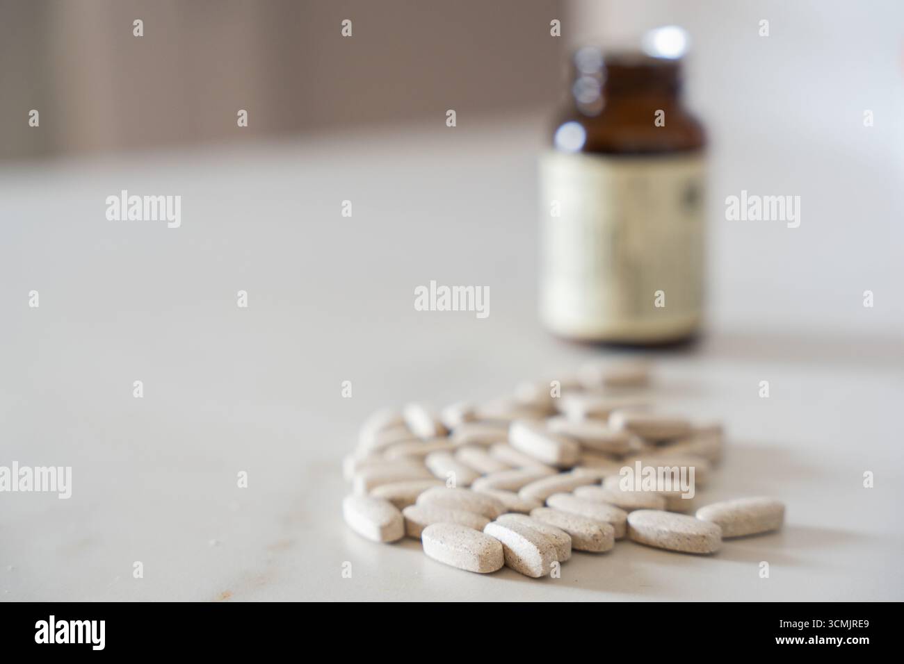 Medizinische Pillen werden aus einer braunen Flasche auf einen weißen Tisch verschüttet und stehen für Gesundheit, Medizin und Behandlung Stockfoto