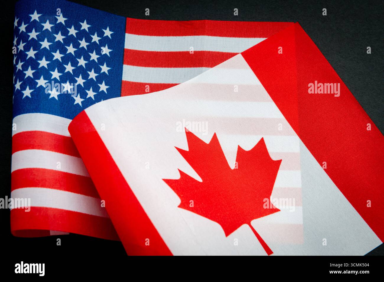 Die Nationalflagge der USA und die Flagge Kanadas isoliert auf Schwarz. Ein Konzept der Beziehungen zwischen den USA und Kanada. Stockfoto