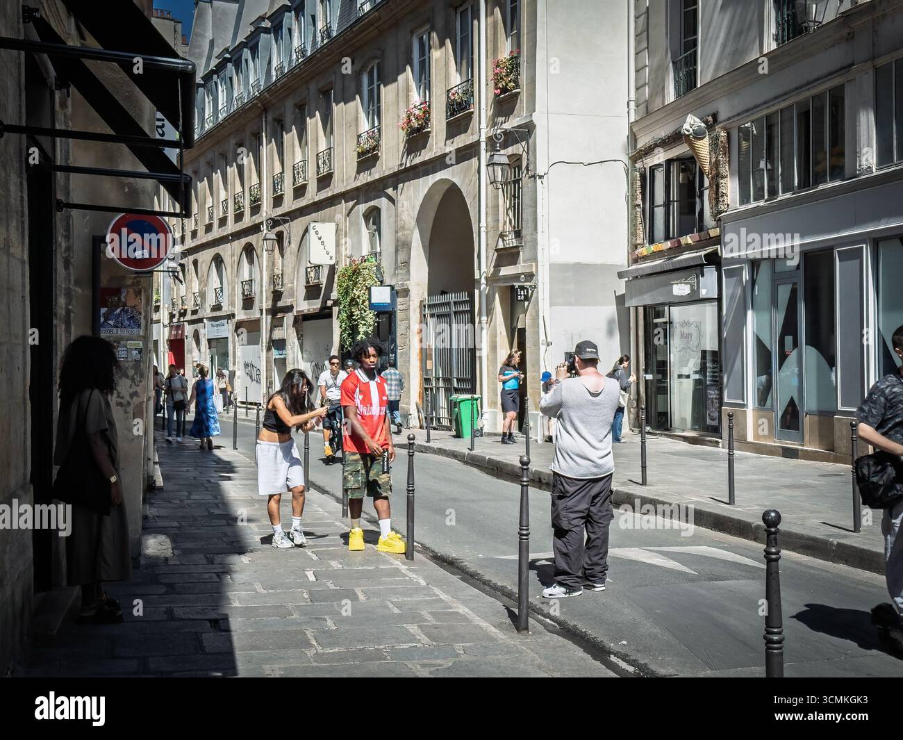 PARIS, FRANKREICH - 24. JUNI 2025: Die Leute posieren für ein Fashion-Fotoshooting auf der Rue du Temple im Pariser Viertel Marais. Ein Fotograf lenkt Models. le Stockfoto