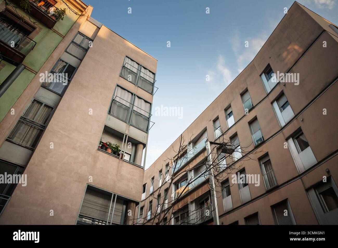 Wohnblöcke bilden einen schmalen Innenhof unter einem klaren Abendhimmel in Barcelona, mit Fenstern, die das Gefühl eines städtischen Wohnens und eines städtischen Wohnens einfangen Stockfoto