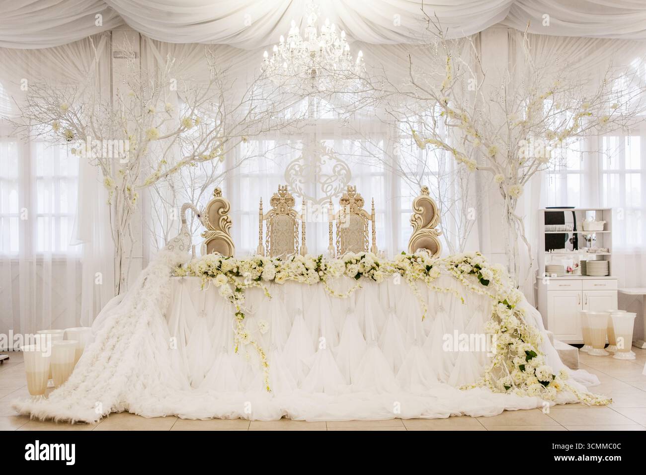 Atemberaubende Hochzeitseinrichtung mit einer aufwendig gestalteten Kulisse mit weißen Blumen und eleganten Dekorationen. Stockfoto