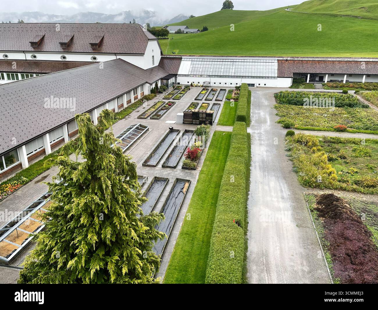 Gewächshaus und Garten in der Schweiz, umgeben von lebendigen, üppigen Landschaften und Wegen im Kloster Einsiedeln Stockfoto