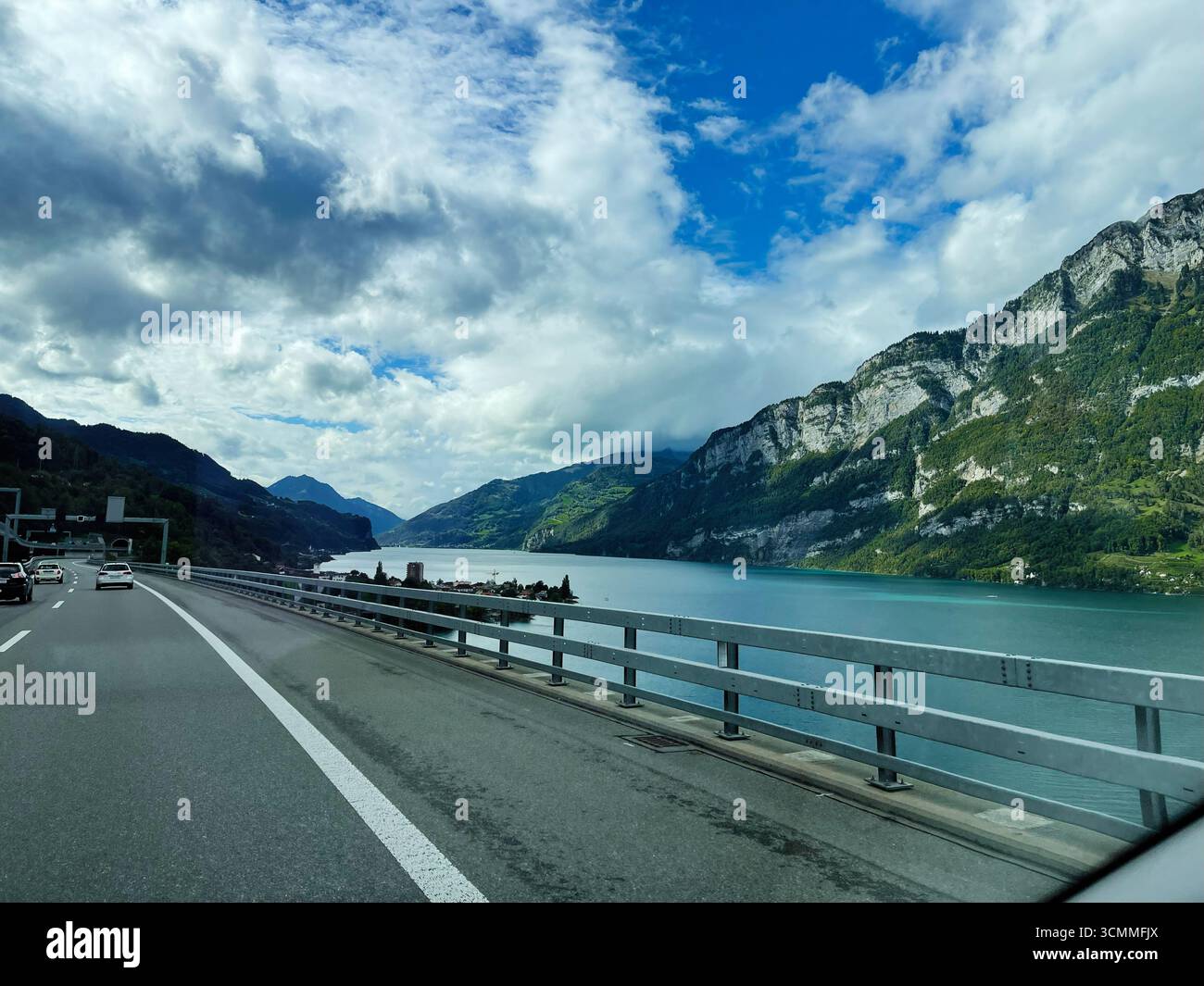Eine pulsierende, malerische Bergfahrt entlang eines Sees unter teilweise bewölktem Himmel in der Schweiz. Stockfoto
