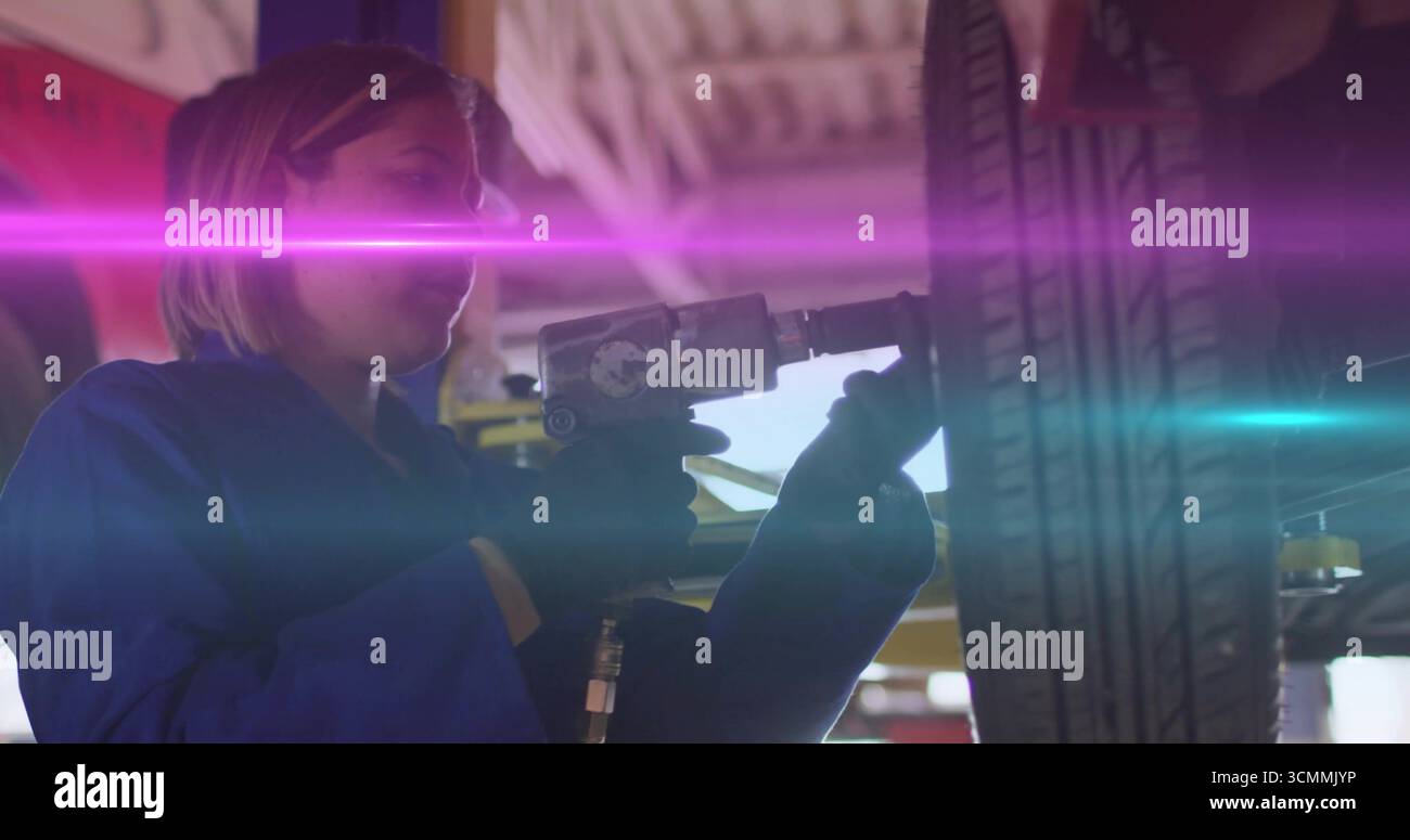 Techniker in blauem Overall mit einem Luftschlagschlüssel zum Lösen der Radmuttern am Autorad in der Werkstatt Stockfoto