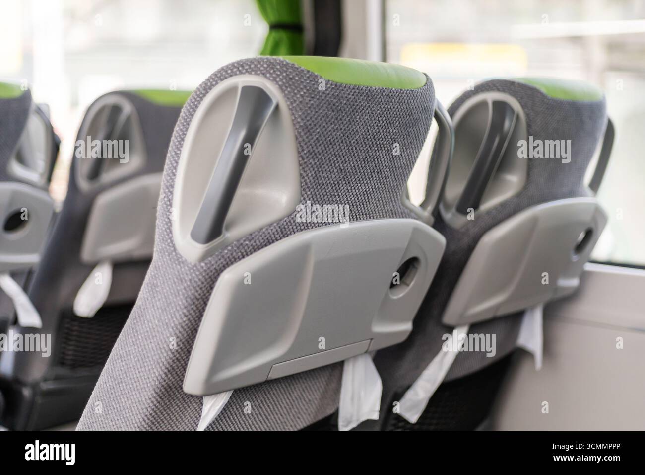 Die Sitzreihen im Bus sind mit weichem grauen Stoff und leuchtenden grünen Details auf Komfort und Stil ausgelegt. Jede Rückenlehne Stockfoto